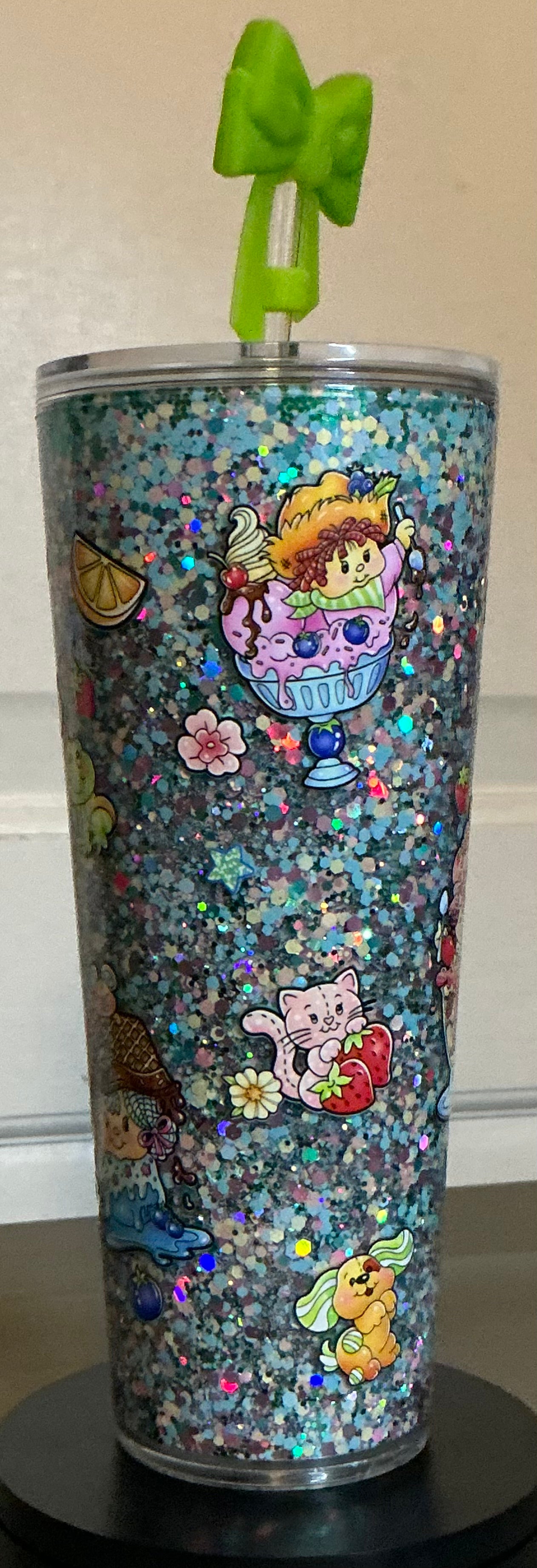 Tumbler with colorful design and green bow on top 